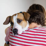 Woman hugs her dog in studio background